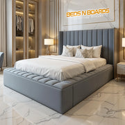 Modern bedroom with a gray upholstered bed and 'BEDS N BOARDS' logo.